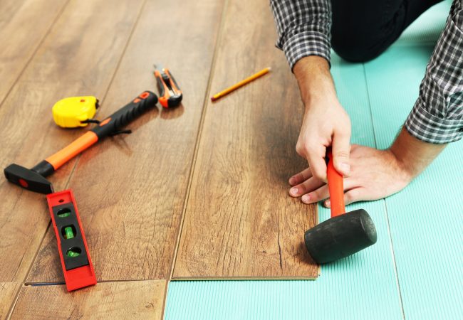 Carpenter worker installing laminate flooring in the room